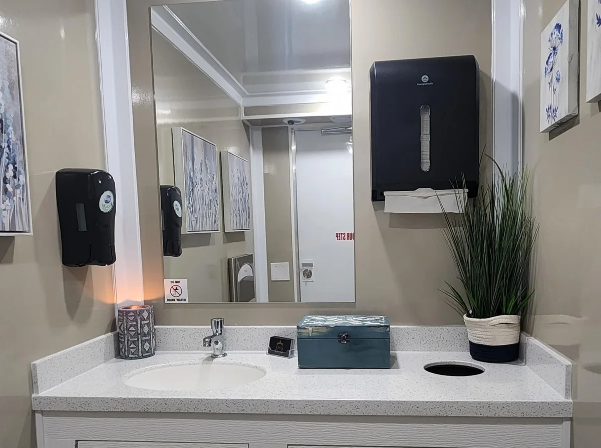 Washbasin, large mirror and wall-mounted dispensers.
