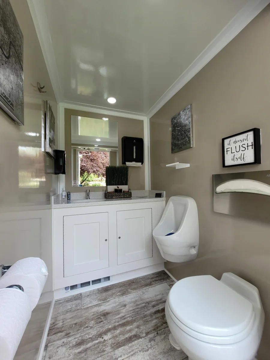 Private restroom with a flushing toilet, urinal and vanity.